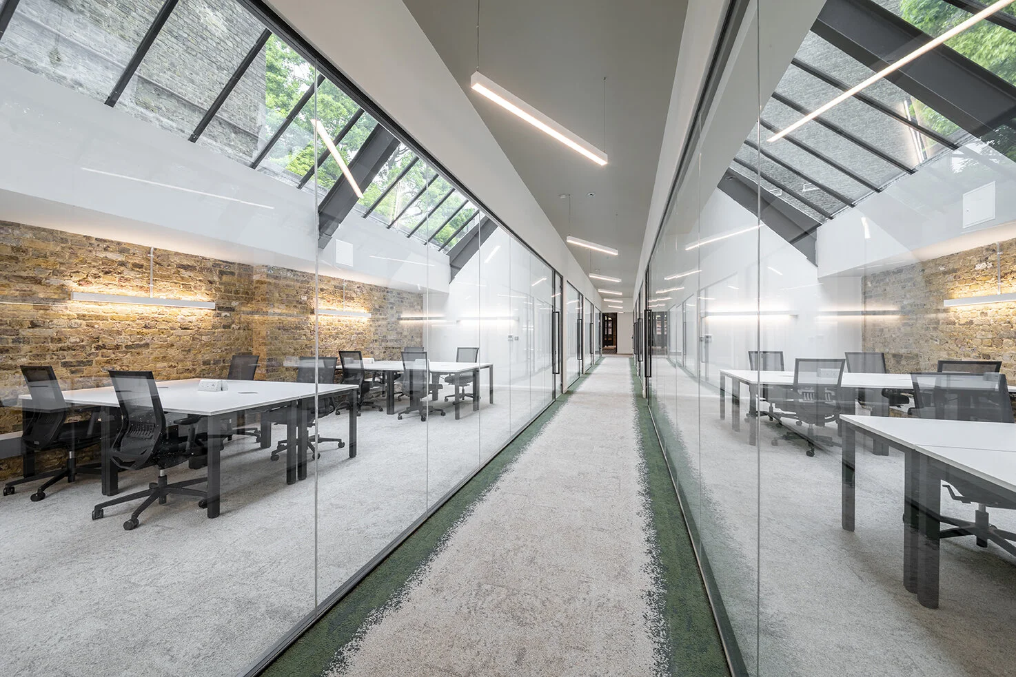 Workspace corridor at The Connolly Works, lined with glass-partitioned offices under skylights